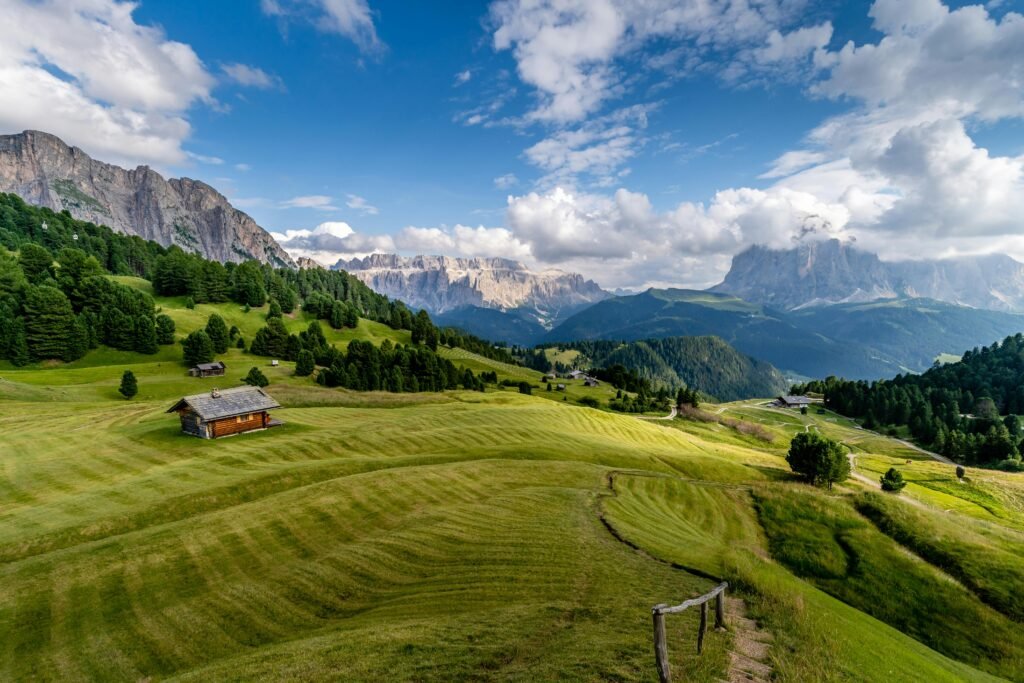 Breathtaking view of rolling hills and mountains in Trentino-South Tyrol, Italy, with clear skies and lush greenery.